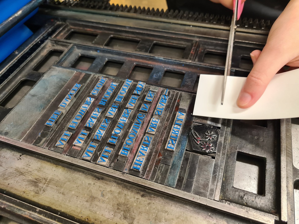 Ein eingefärbter Satz liegt auf einem Drucktisch und die Höhe eines Klischees wird verändert.
